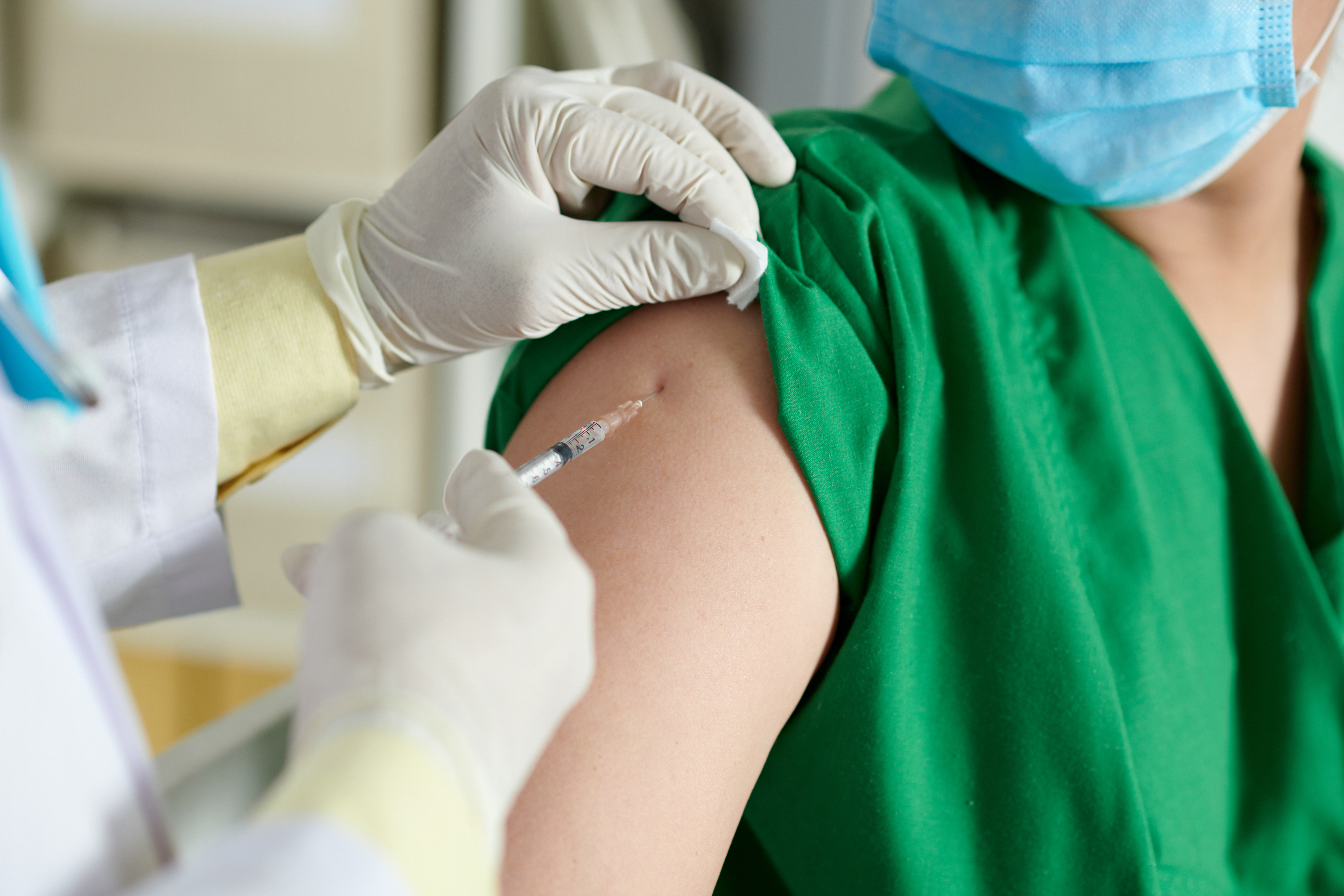 Close-up image of doctor making injection of vaccine in shoulder of medical nurse