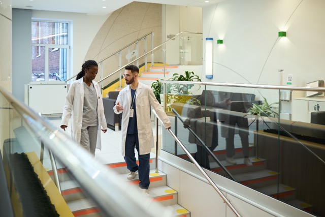 Two physicians talking while walking through a medical office building, illustrating physician group deals and lease considerations
