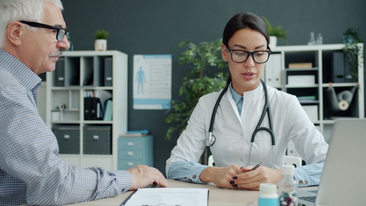 Medical professional discusses health with senior man in modern office setting. Tampa Bay outpatient real estate